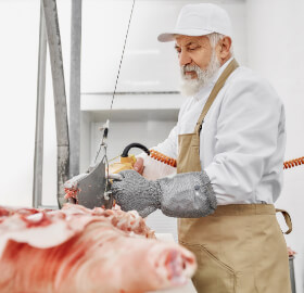 Butcher holding a meat saw which is holding by Tecna balancer